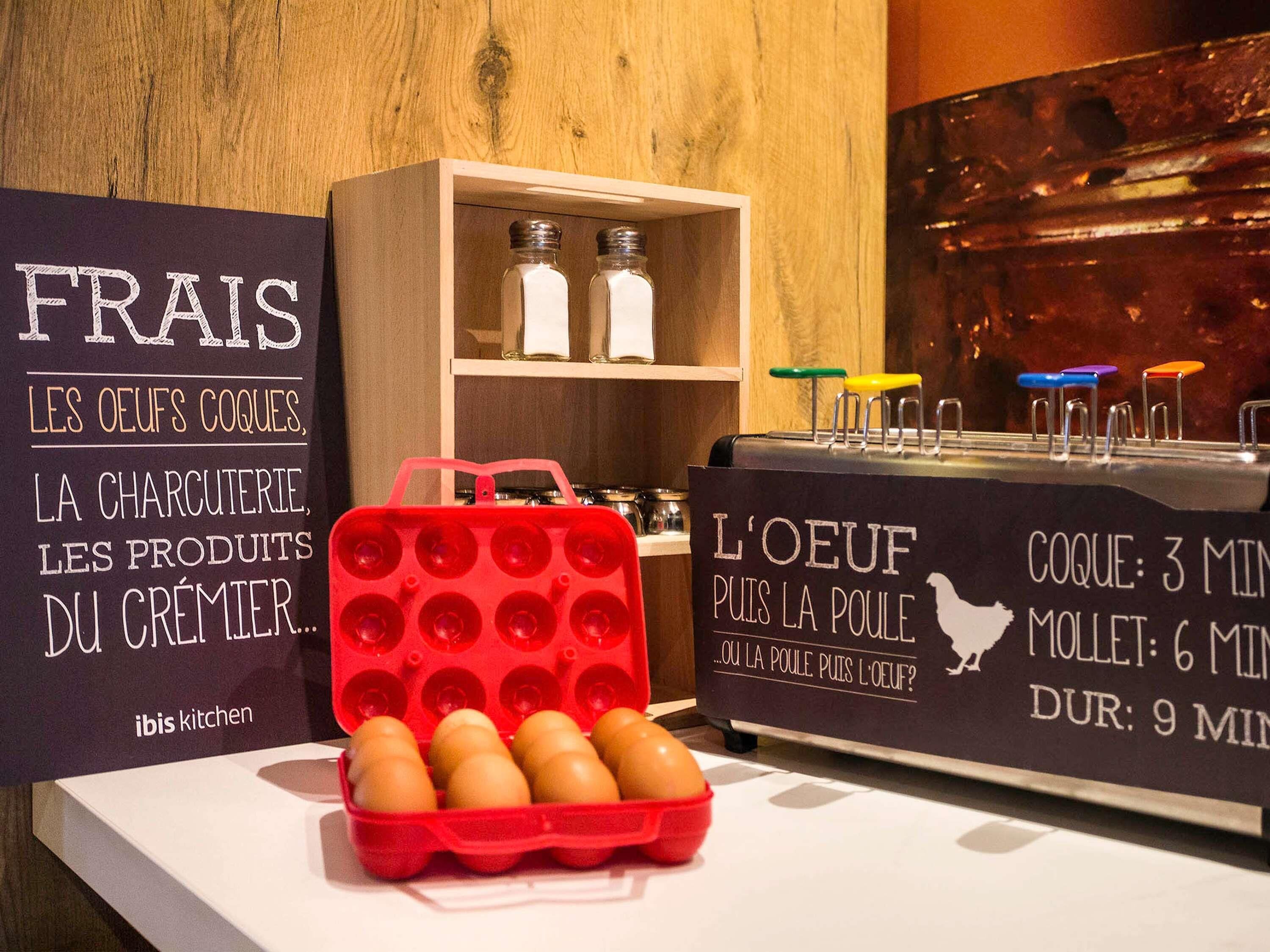 A kitchen counter with a red egg tray, two signs with French text, and a shelf with salt shakers.