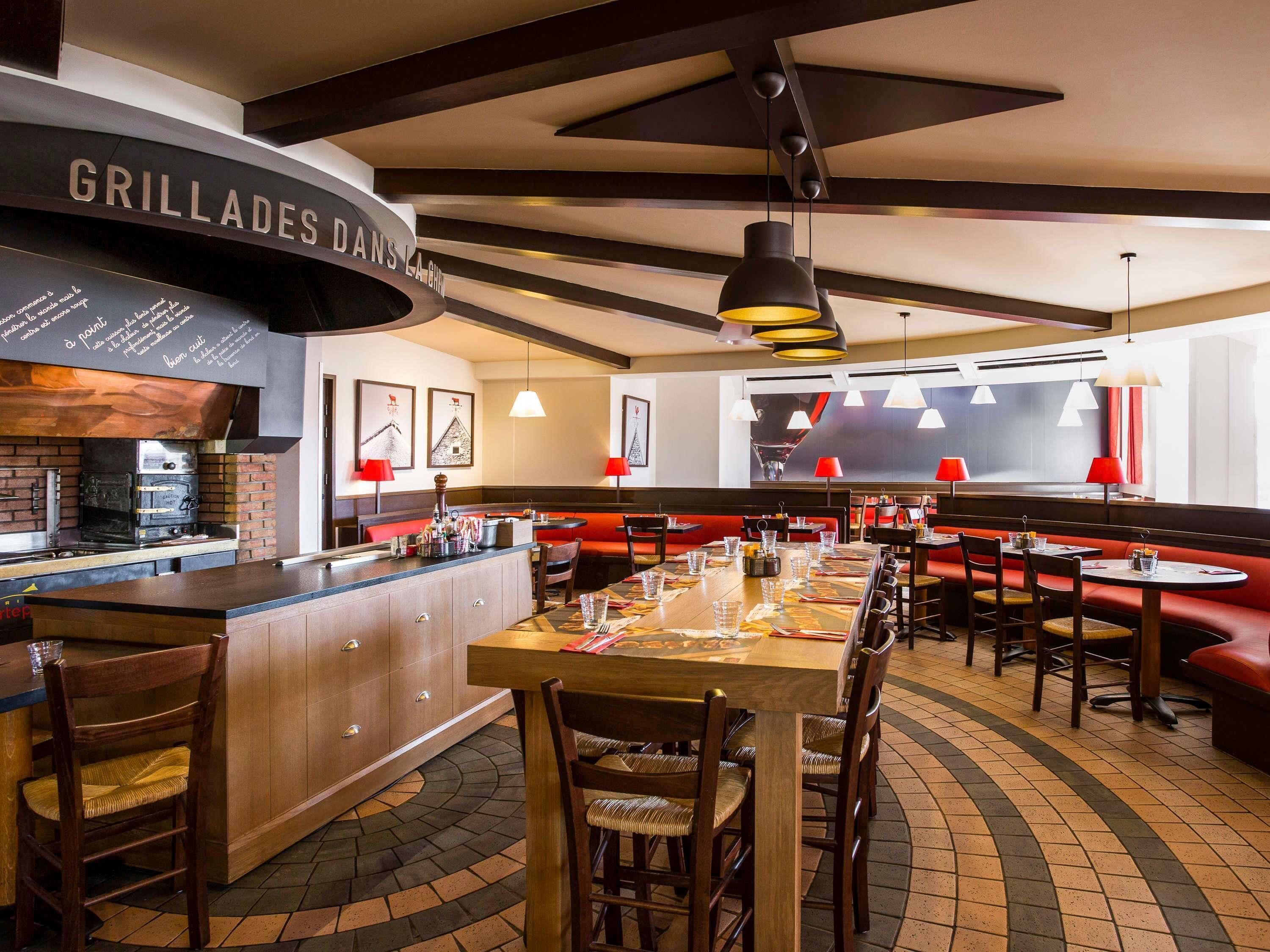 Interior de restaurante con barra, mesas de madera y cabinas rojas.