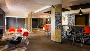 A modern bar area with red and black chairs, a wooden pillar with 'bar' written on it, and a patterned wall. - ibis Bordeaux Lac (Bordeaux)