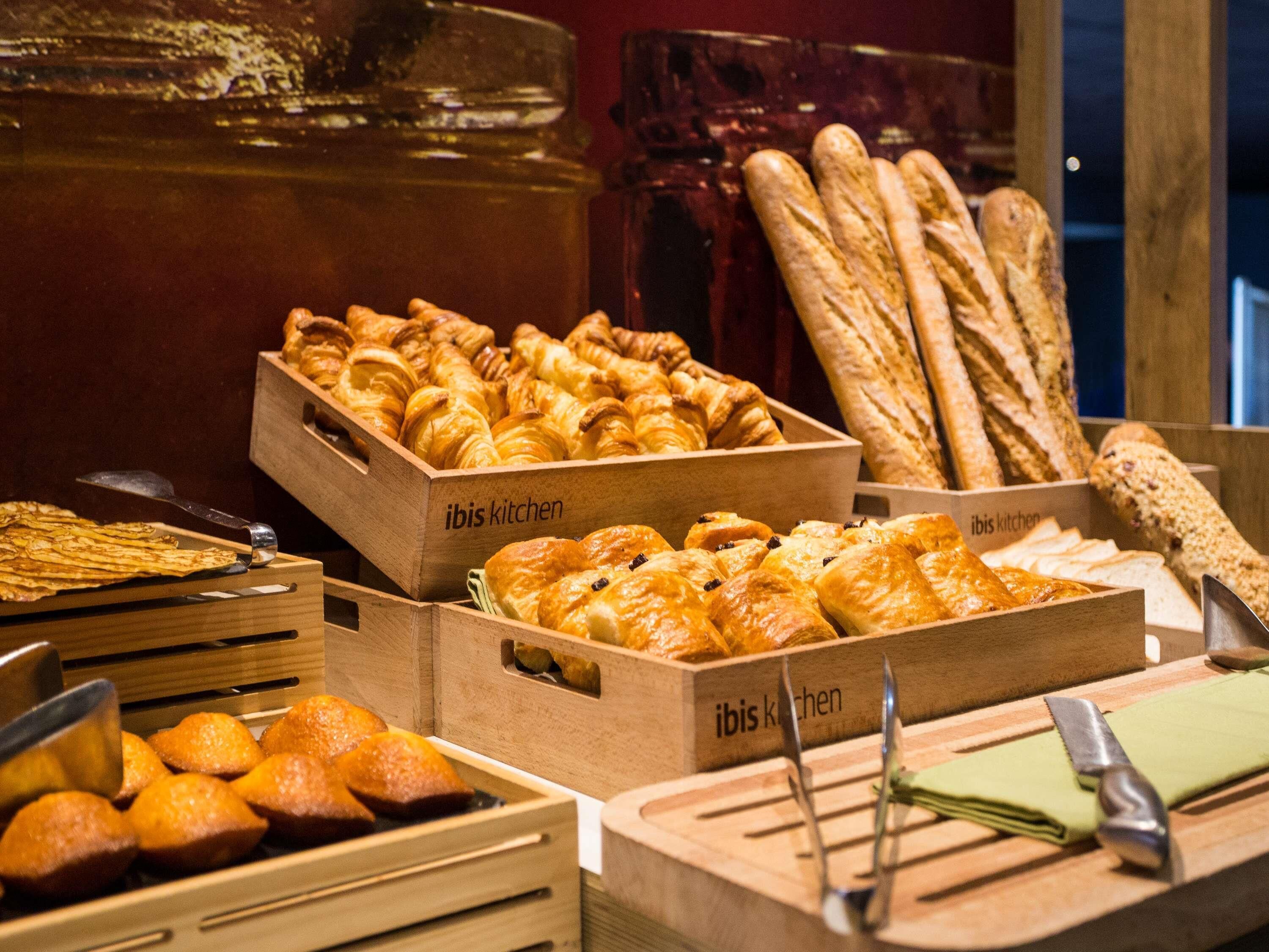 A variety of baked goods displayed in wooden boxes labeled 'ibis kitchen'.