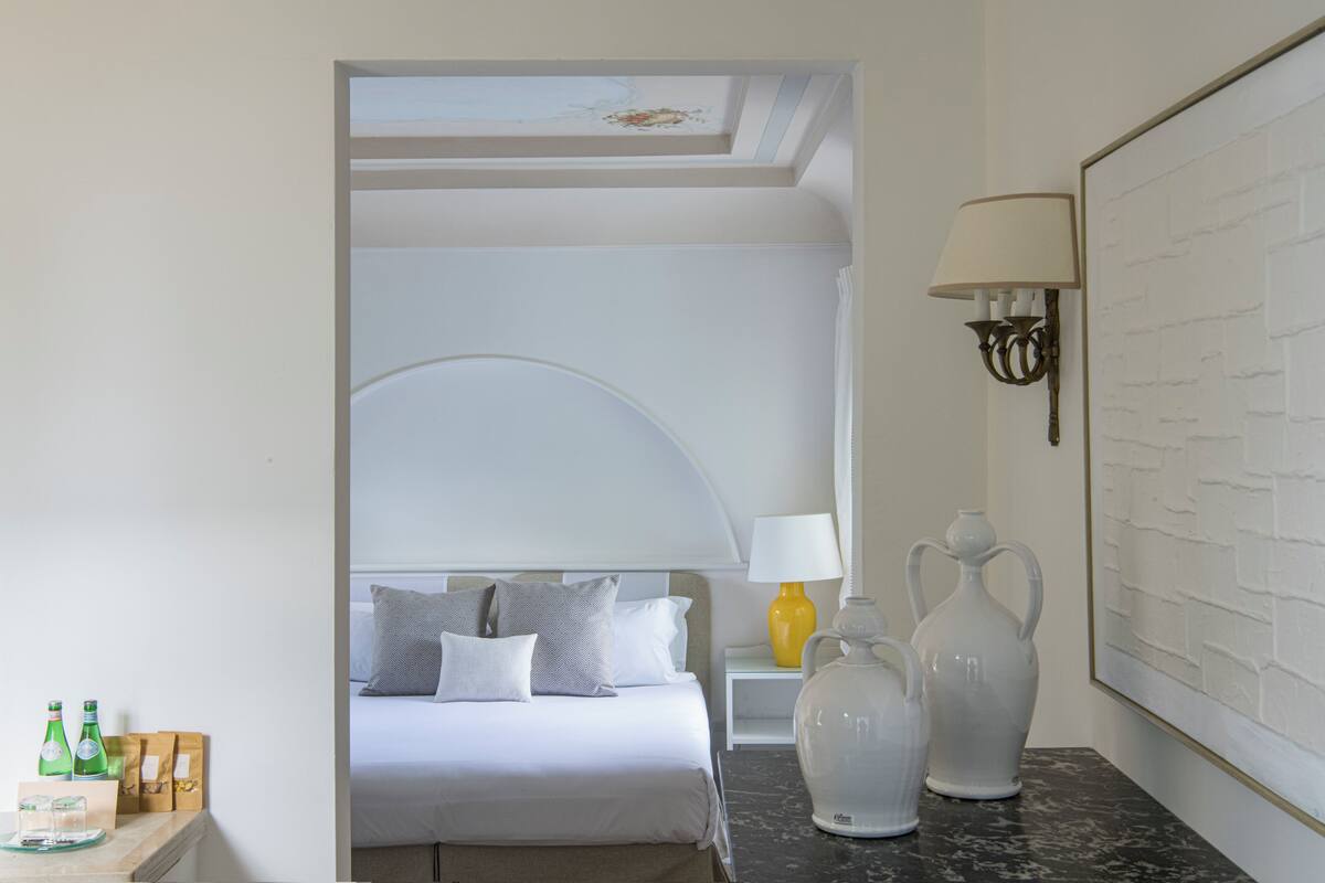 Une chambre d’hôtel avec un lit, une table de chevet, une lampe et un vase.