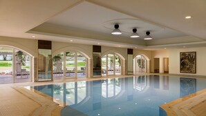 An indoor swimming pool with clear glass walls, a tiled floor, and a ceiling with recessed lighting. - Il Melograno (Monopoli)