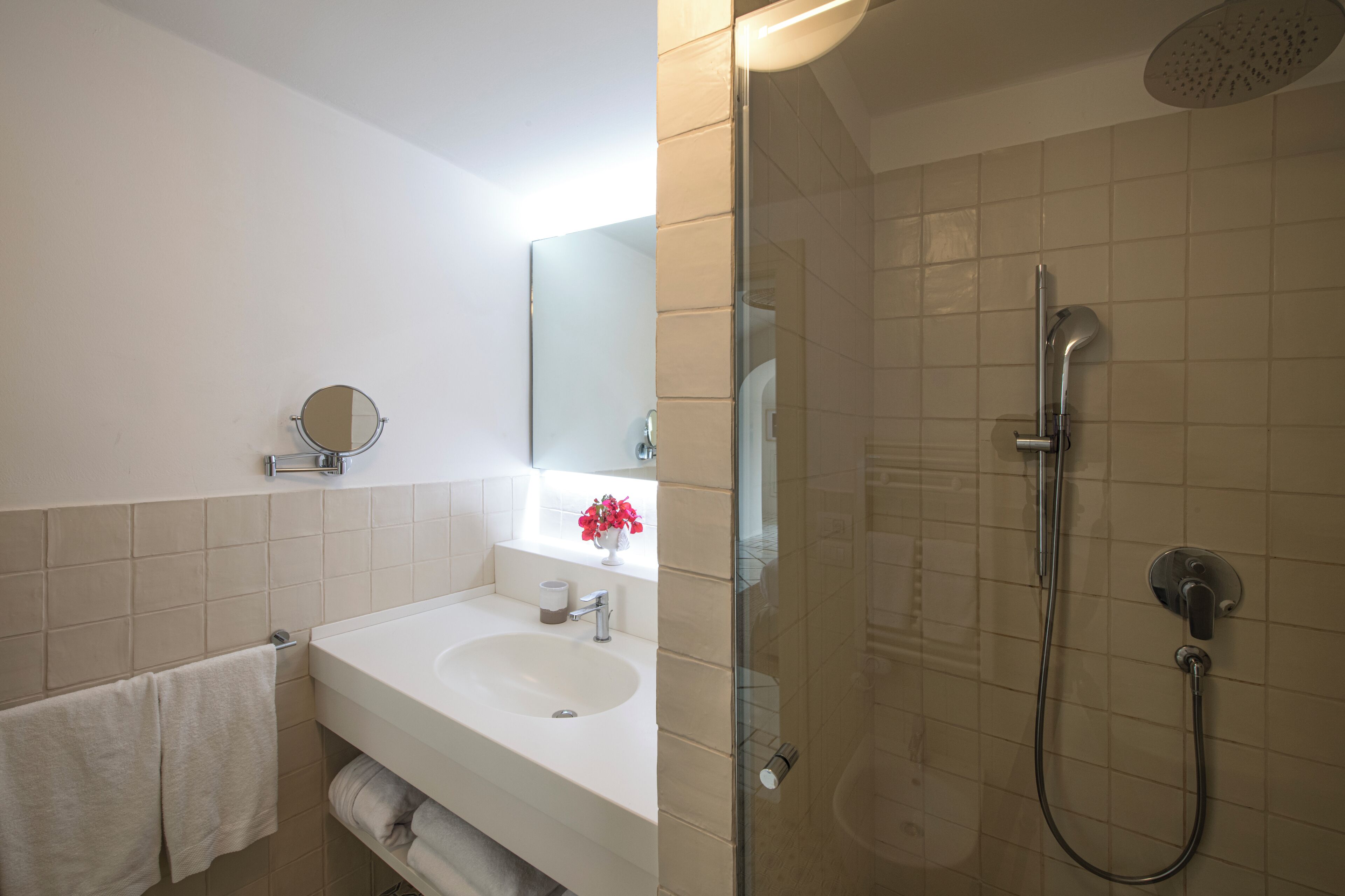 A bathroom with a sink, mirror, and shower.