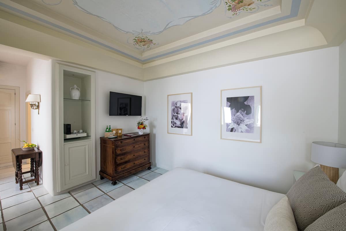 Une chambre à coucher avec un lit, une commode, un téléviseur et des tableaux encadrés accrochés au mur.