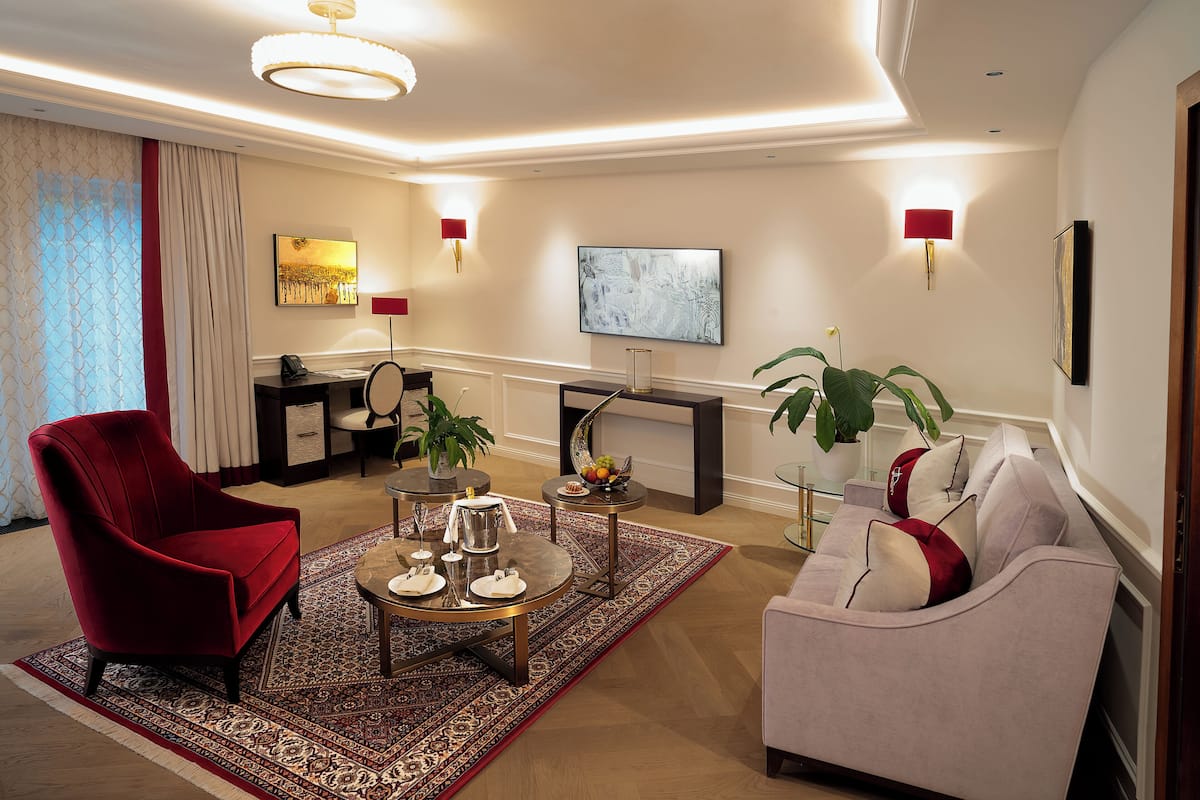 A modern living room with a red armchair, a white sofa, a round coffee table, and a TV mounted on the wall.