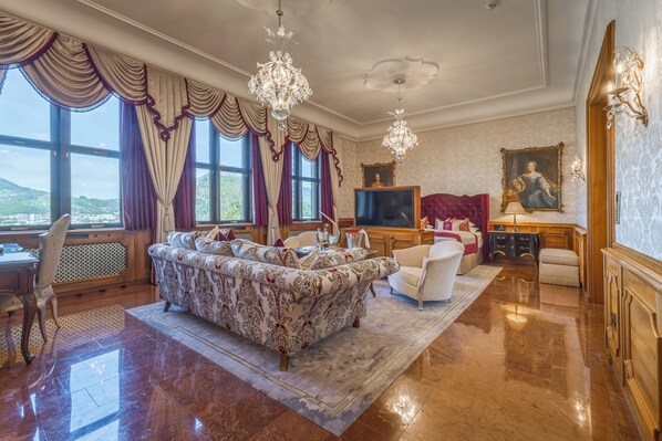 A spacious living room with a large sofa, a television, and a view of the outdoors.