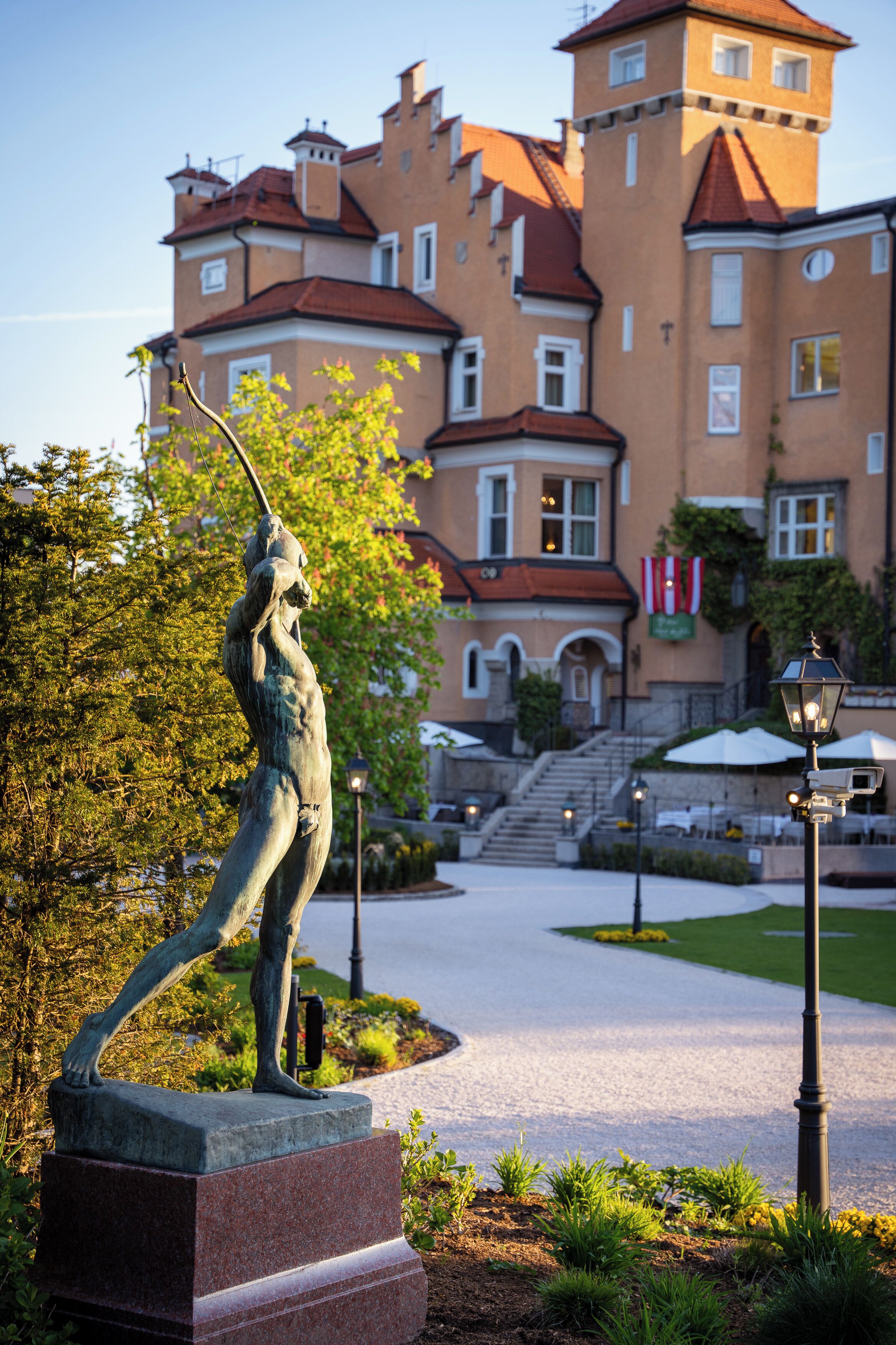 A statue in a garden with a building in the background.