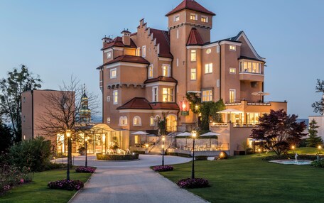 A large, multi-story hotel with a central courtyard, outdoor seating, and a well-lit entrance.