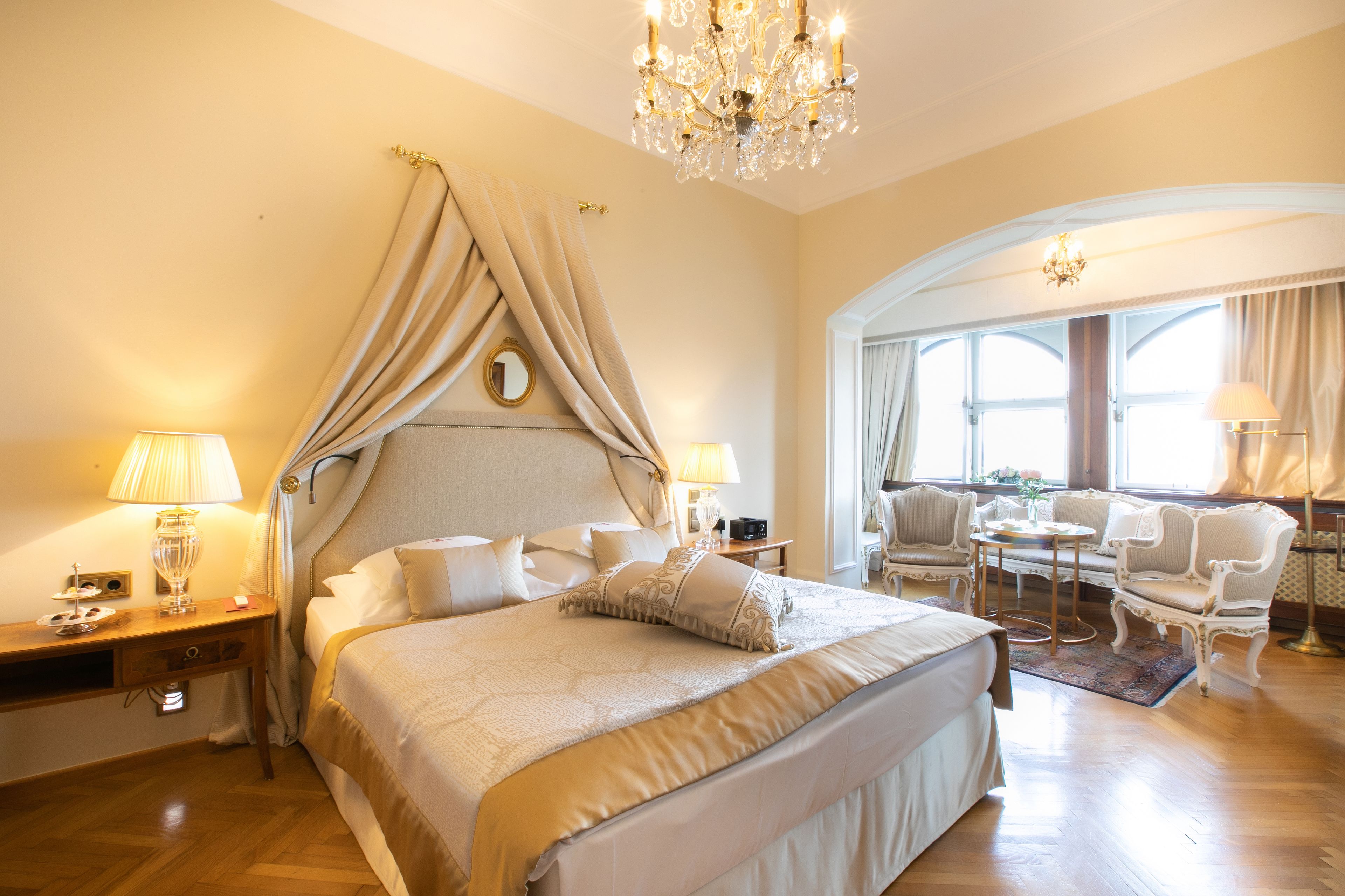 A spacious bedroom with a large bed, a chandelier, and a seating area with a table and chairs.
