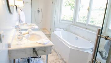 Une salle de bain moderne dotée d’une grande baignoire, d’une douche séparée et d’un meuble-lavabo avec un miroir.
