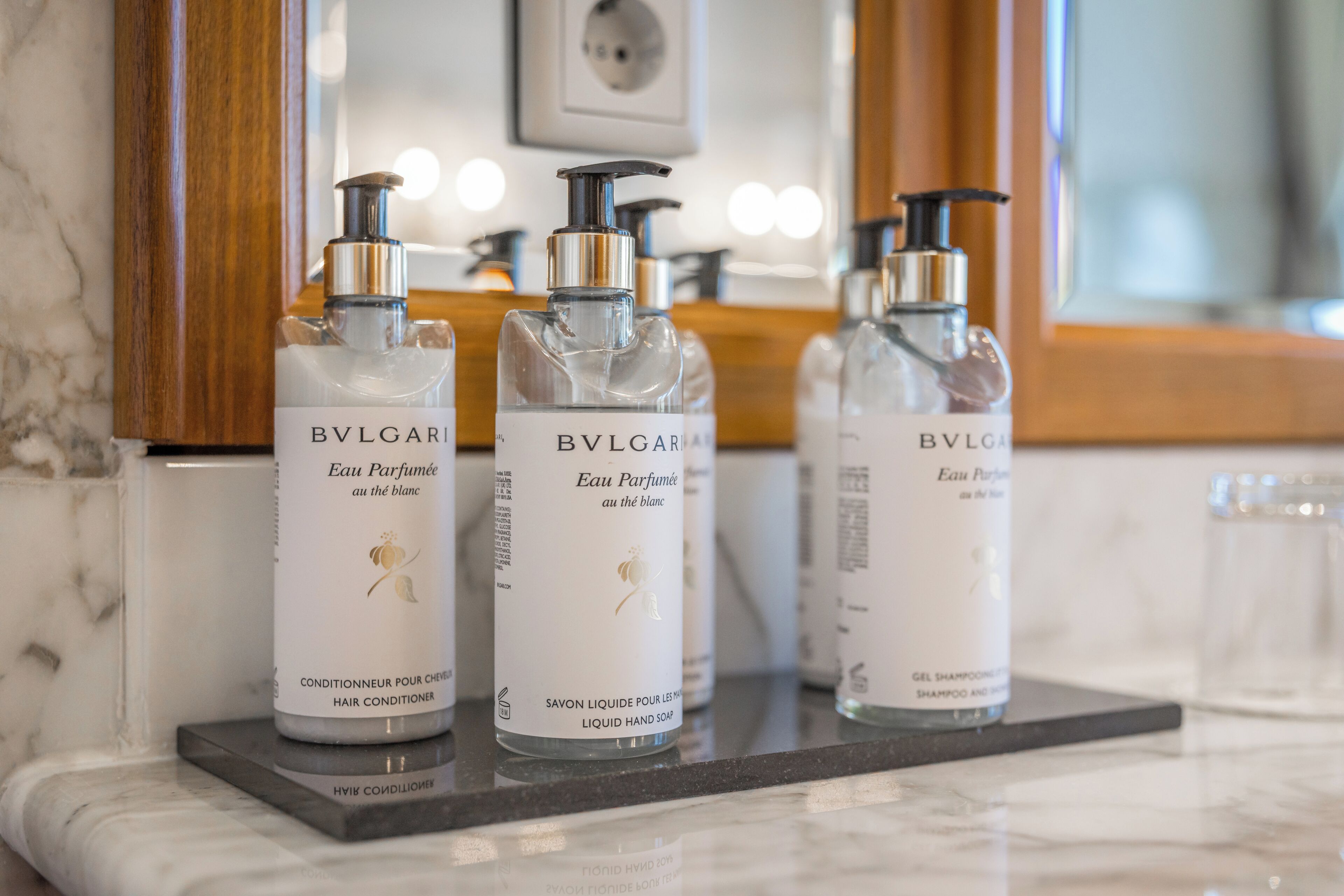 Three bottles of BVLGARI Eau de Parfum on a marble countertop.