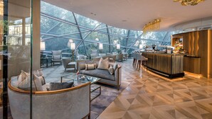 Un interior moderno con techo de cristal, zona de bar y diferentes disposiciones de asientos.