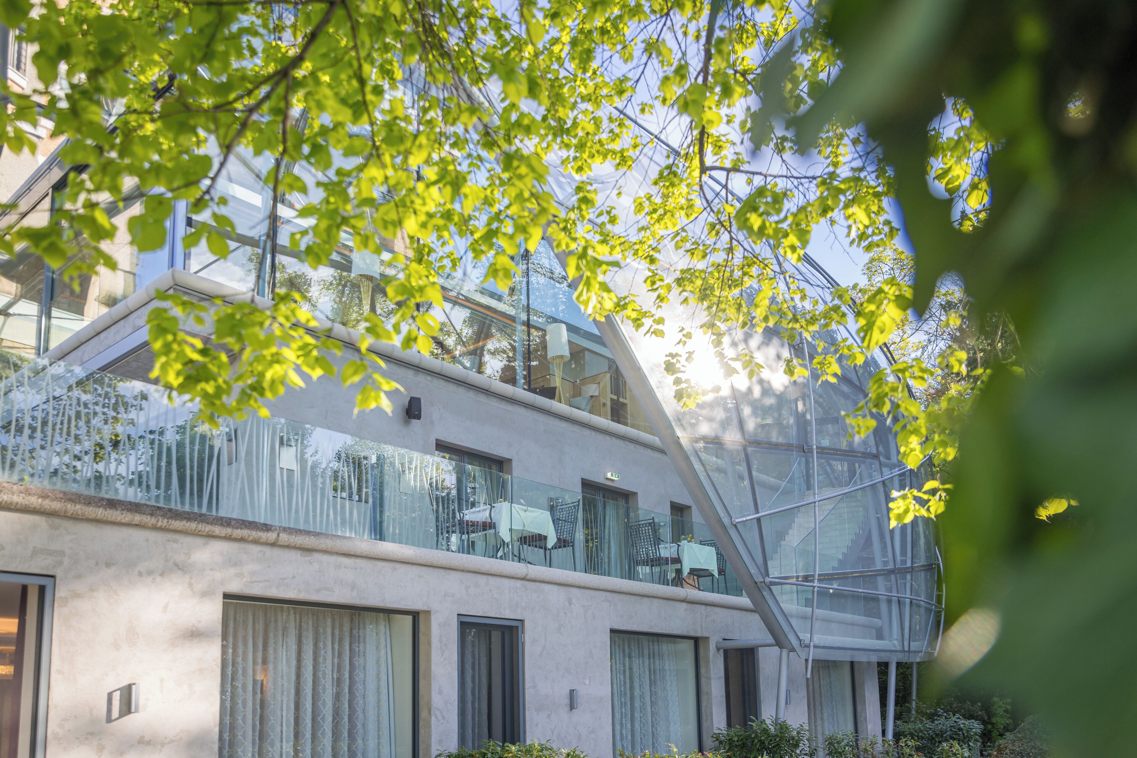 A modern building with a glass balcony, large windows, and a view of the sky.