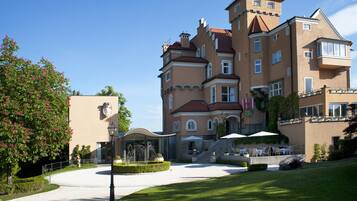 A large, multi-story building with a central courtyard, outdoor seating area, and a fountain.