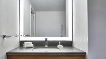 Un baño con un tocador moderno, un espejo y un grifo.