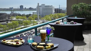 A terrace with tables set for dining, overlooking a cityscape with a bridge and buildings.
