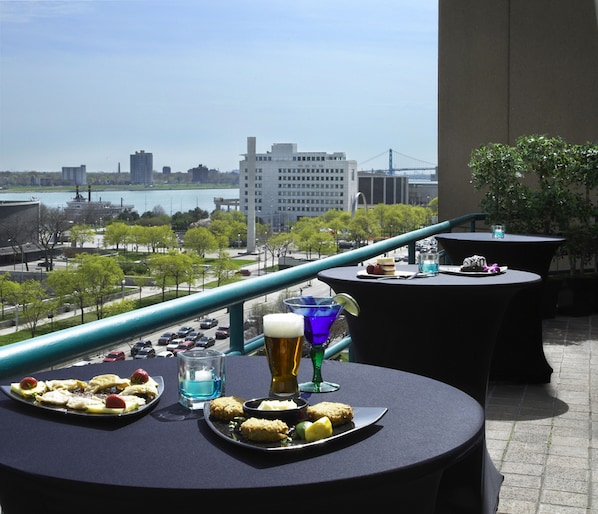 A terrace with tables set for dining, overlooking a cityscape with a bridge and buildings. - Courtyard By Marriott Detroit Downtown (Detroit)