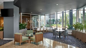 A modern indoor space with seating areas, a dining table, and large windows offering views of the outdoors.