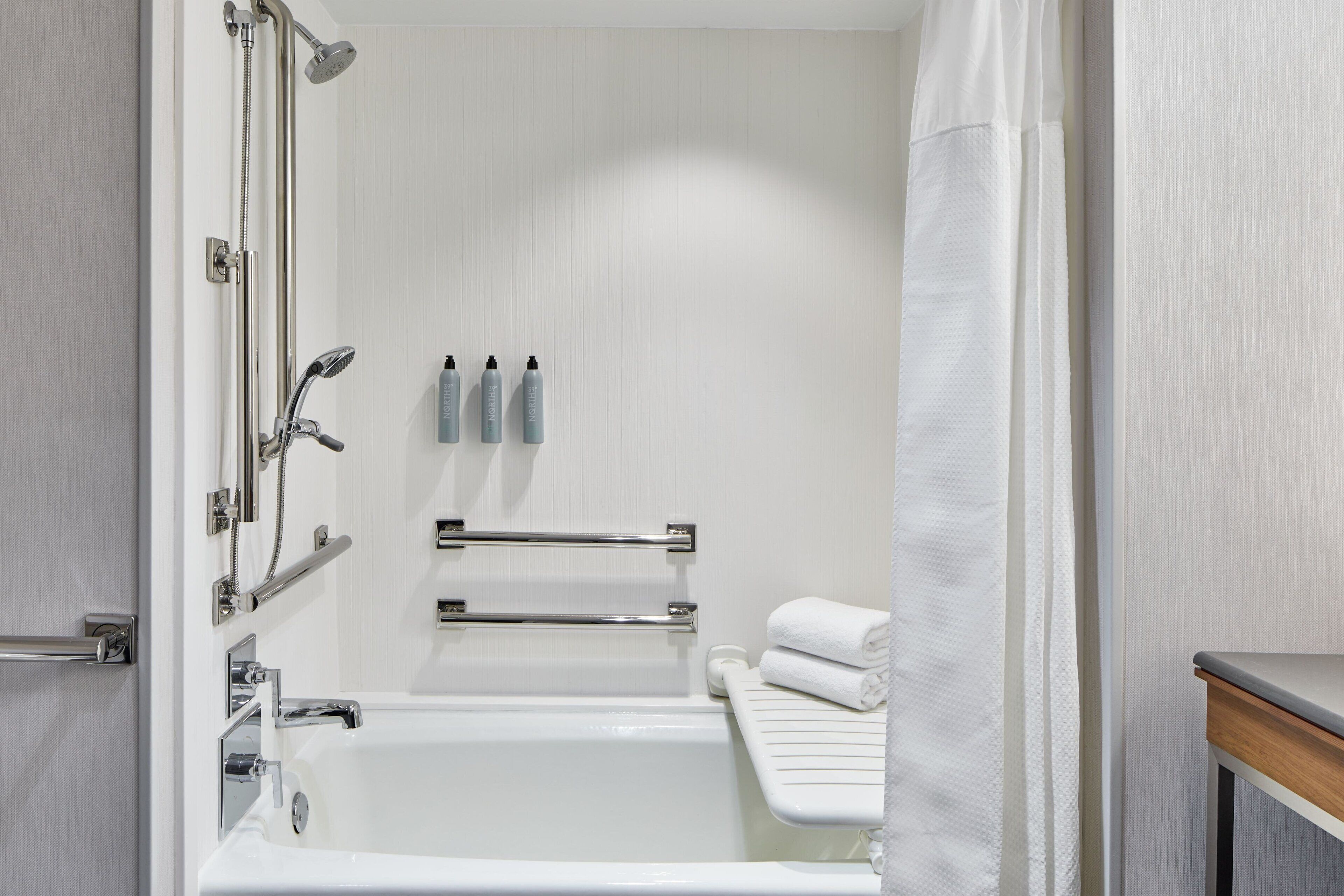 A modern bathroom with a bathtub, shower, and towel rack.
