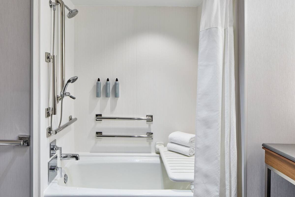 A modern bathroom with a bathtub, shower, and towel rack.
