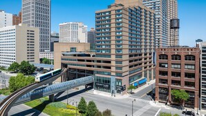 A modern hotel with a prominent 'Courtyard by Marriott' sign, a covered walkway, and a train track. - Courtyard By Marriott Detroit Downtown (Detroit)