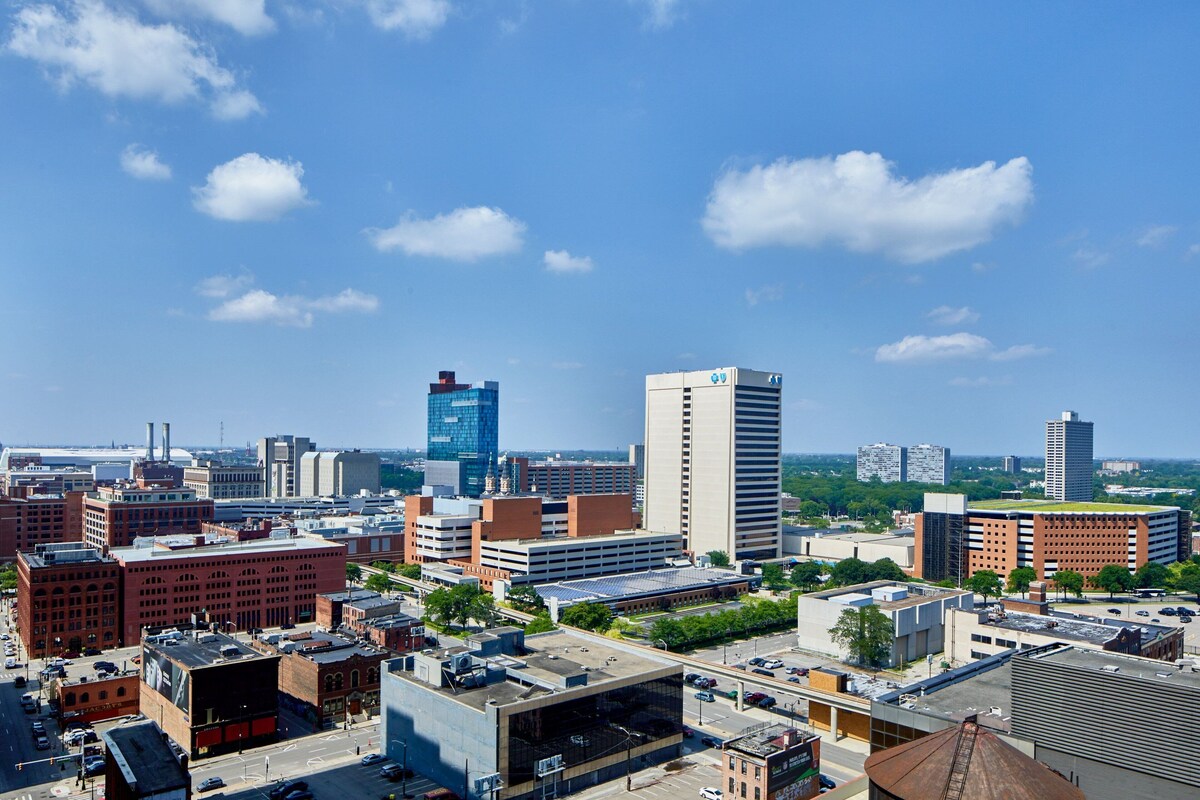 A cityscape with various buildings, including a prominent glass skyscraper and several brick structures.