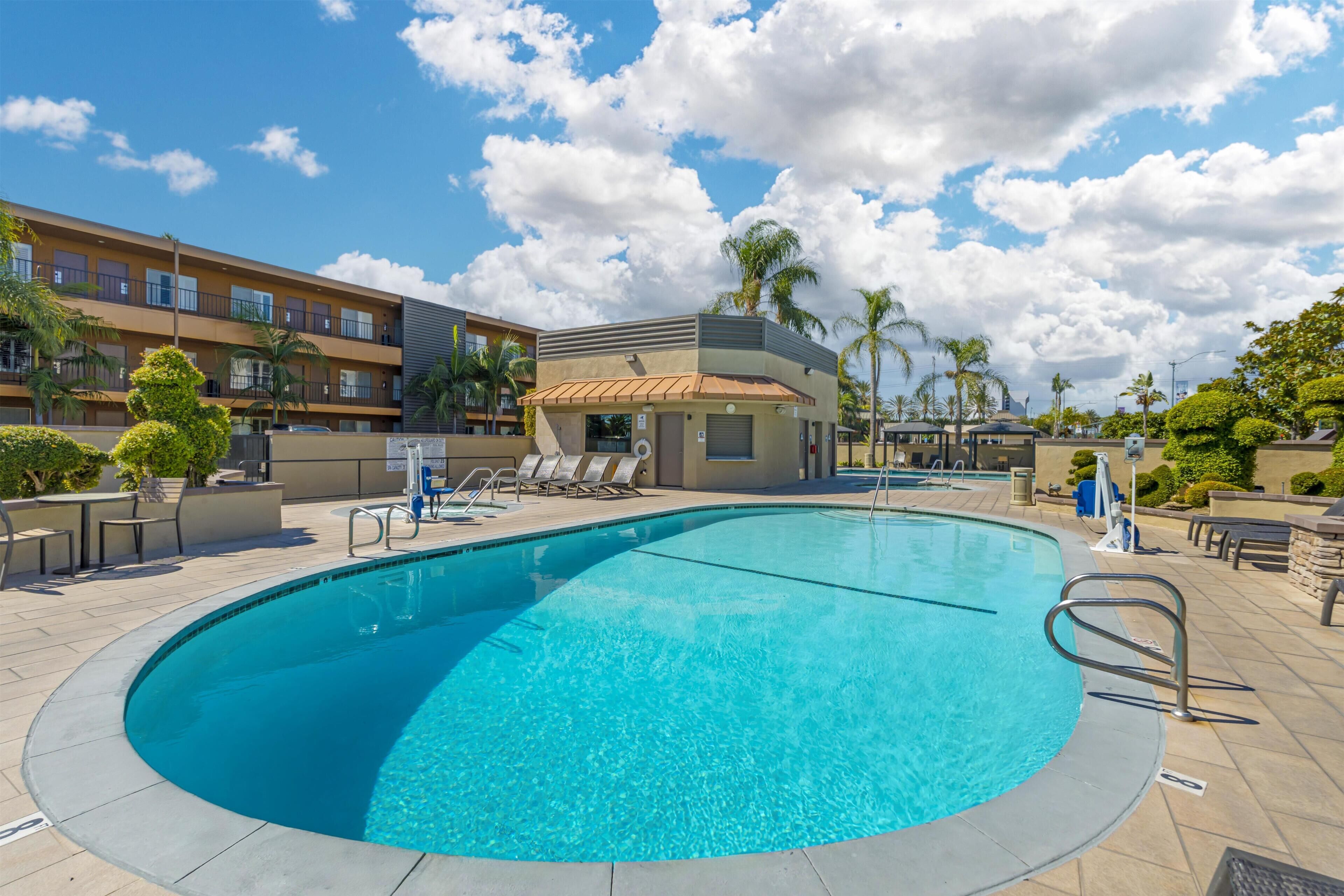 A swimming pool with lounge chairs and a small building with a sloped roof.
