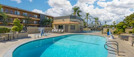 A swimming pool with lounge chairs and a small building with a sloped roof.