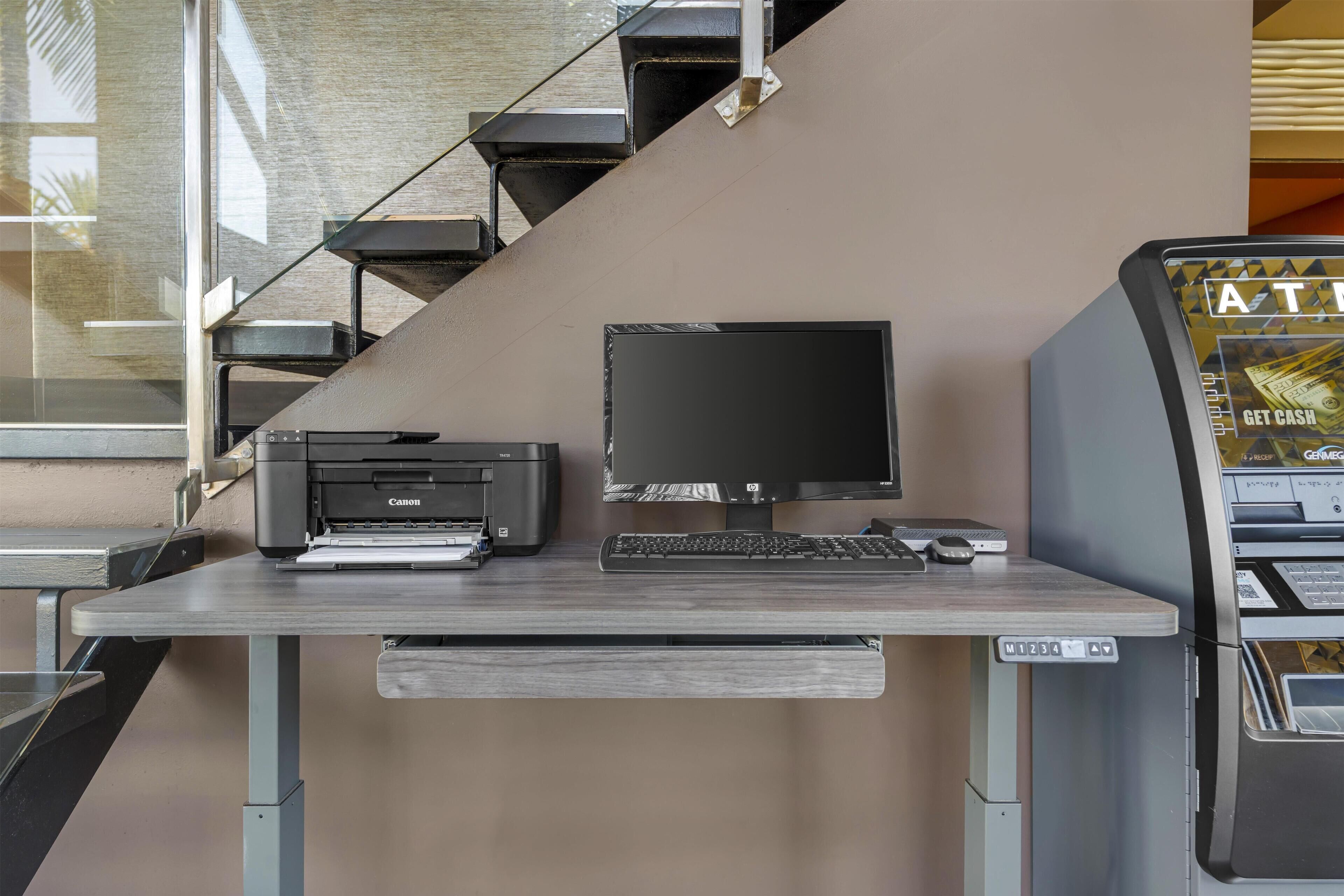 Un'area dedicata al lavoro con una stampante Canon, un computer desktop e un bancomat.