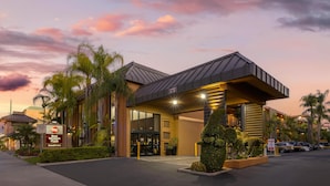 A hotel entrance with a modern design, a Best Western sign, and a parking area.