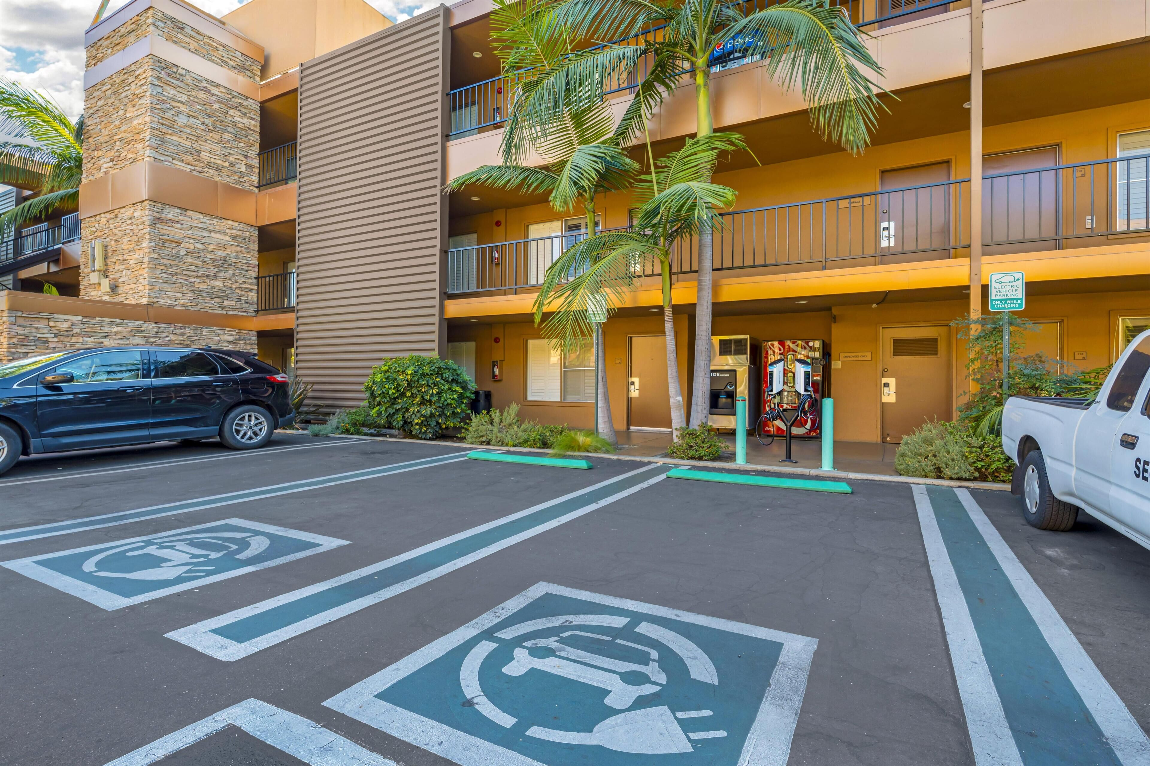 A multi-story hotel with a stone facade, parking spaces marked for electric vehicles, and a sign indicating a pet-friendly policy.