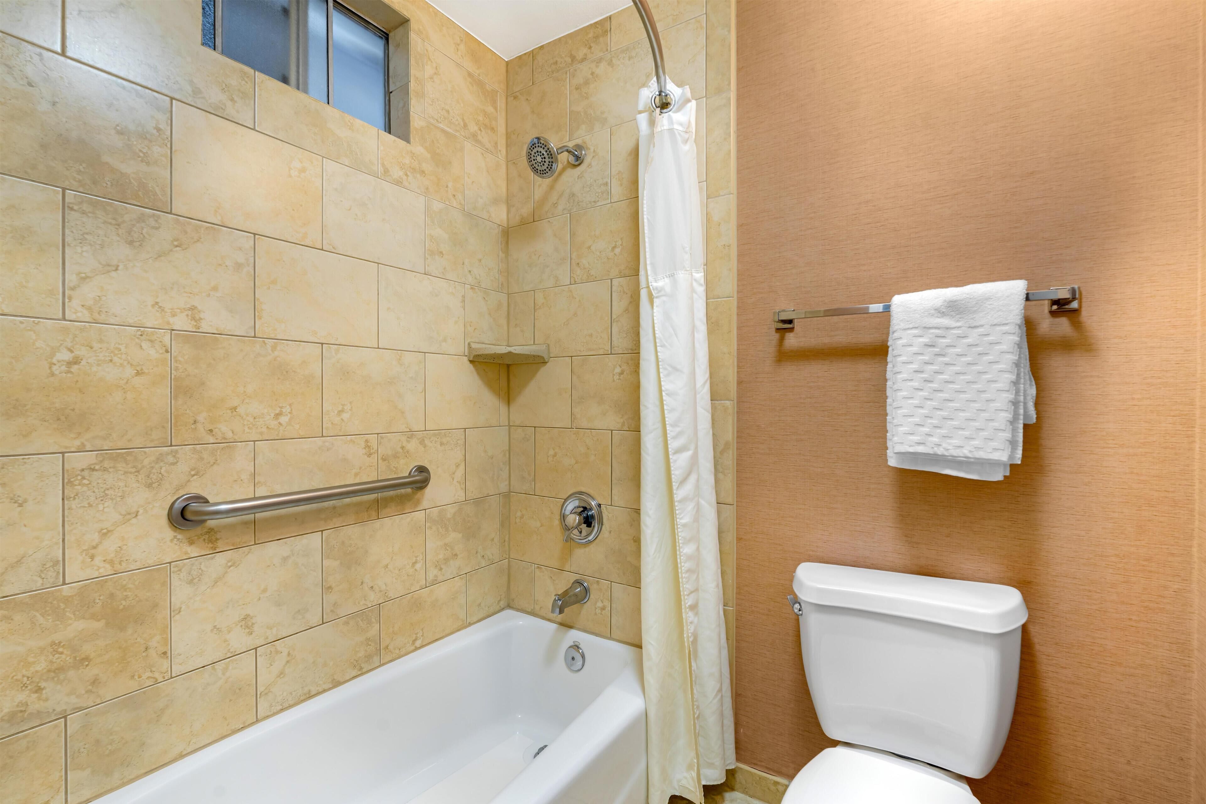 A bathroom with a bathtub, shower, and toilet.