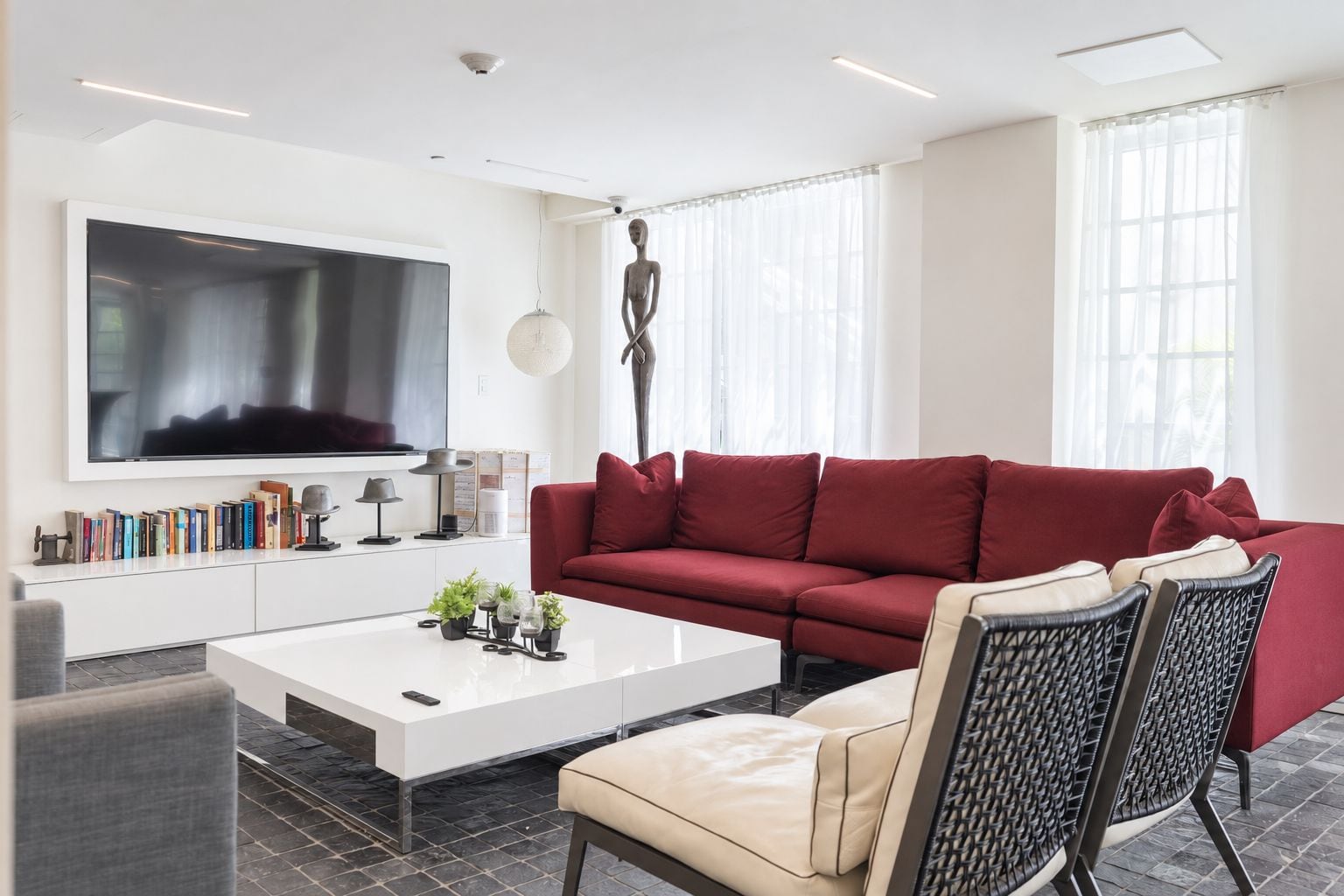 A modern living room with a red sofa, a white coffee table, and a TV mounted on the wall.