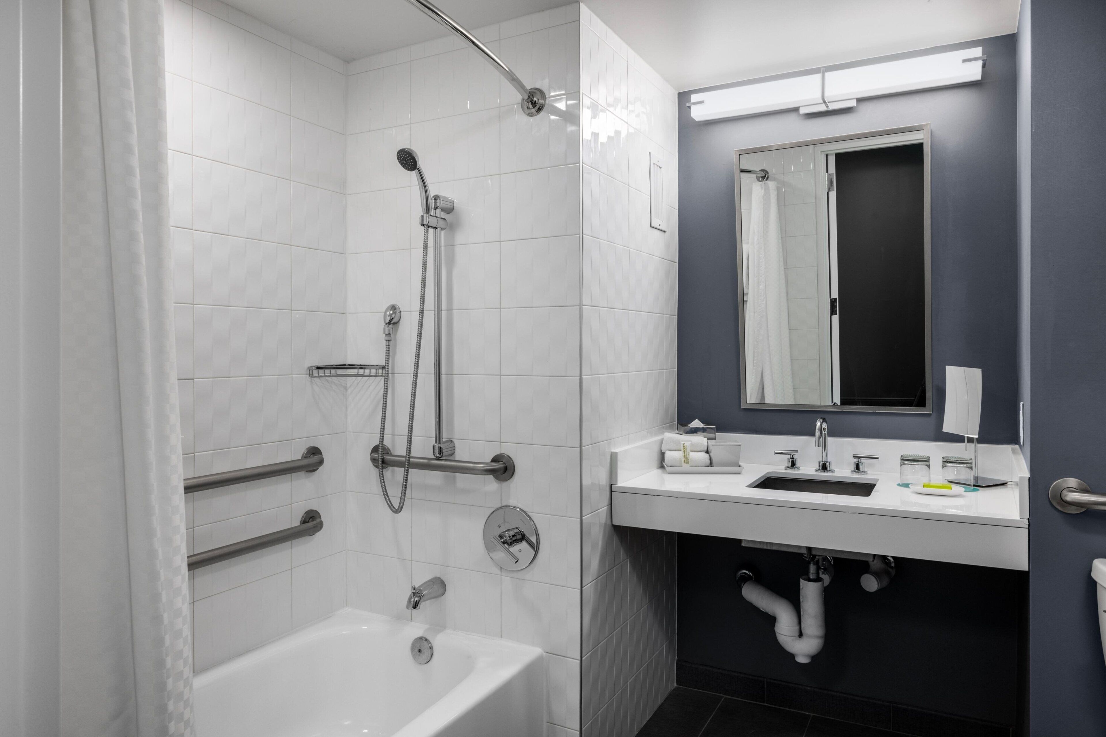 A modern bathroom with a bathtub, shower, and sink.