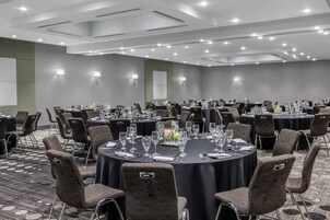 Un salón de conferencias con mesas redondas, sillas y piso alfombrado.
