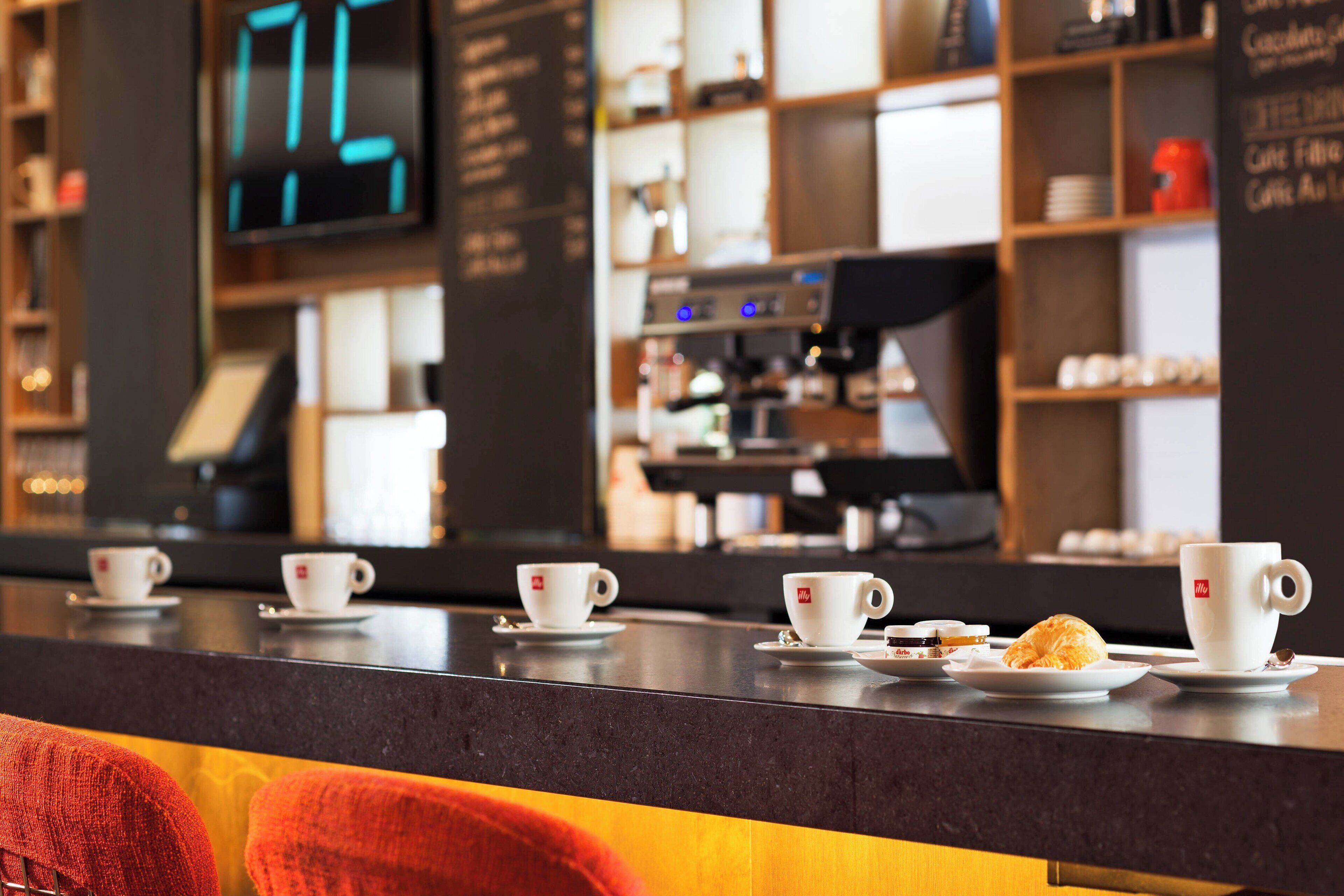 A coffee shop counter with multiple cups and a croissant.