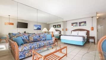 A hotel room with a sofa, a bed, a glass coffee table, and a TV.