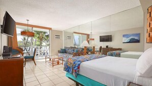 A hotel room with a bed, a desk, a chair, a TV, and a balcony with a view of palm trees.