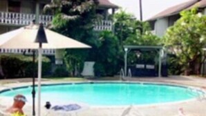 A swimming pool with lounge chairs and an umbrella.