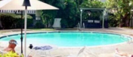 Una piscina con sillas de descanso y una sombrilla.