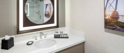 A modern bathroom with a large mirror, a sink, and a toilet.