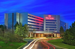 Un hotel Sheraton con diseño moderno, que destaca un prominente logotipo rojo en el edificio.