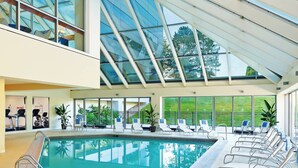 An indoor swimming pool with lounge chairs and exercise equipment.