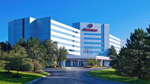 A Sheraton hotel with a modern glass facade, a central entrance, and a well-maintained lawn.