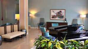 A grand piano in a spacious living area with comfortable seating and a large painting on the wall. - Dorchester Hotel (Miami Beach)