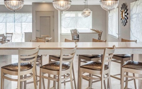 A dining area with a long table, multiple chairs, and three hanging crystal chandeliers.
