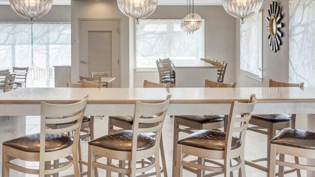 Un espace repas comprenant une longue table, plusieurs chaises et trois lustres en cristal suspendus au plafond.