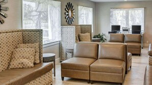 A spacious living room with a brown leather sofa, patterned armchairs, and a large wall clock. - Comfort Inn Williamsburg Gateway (Williamsburg)