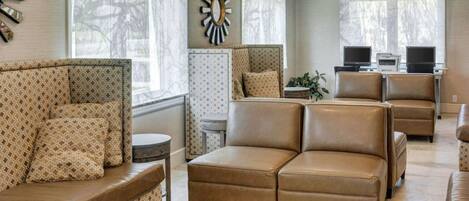 A spacious living room with a brown leather sofa, patterned armchairs, and a large wall clock.