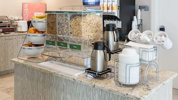 A self-service breakfast station with cereal, fruits, and coffee options.